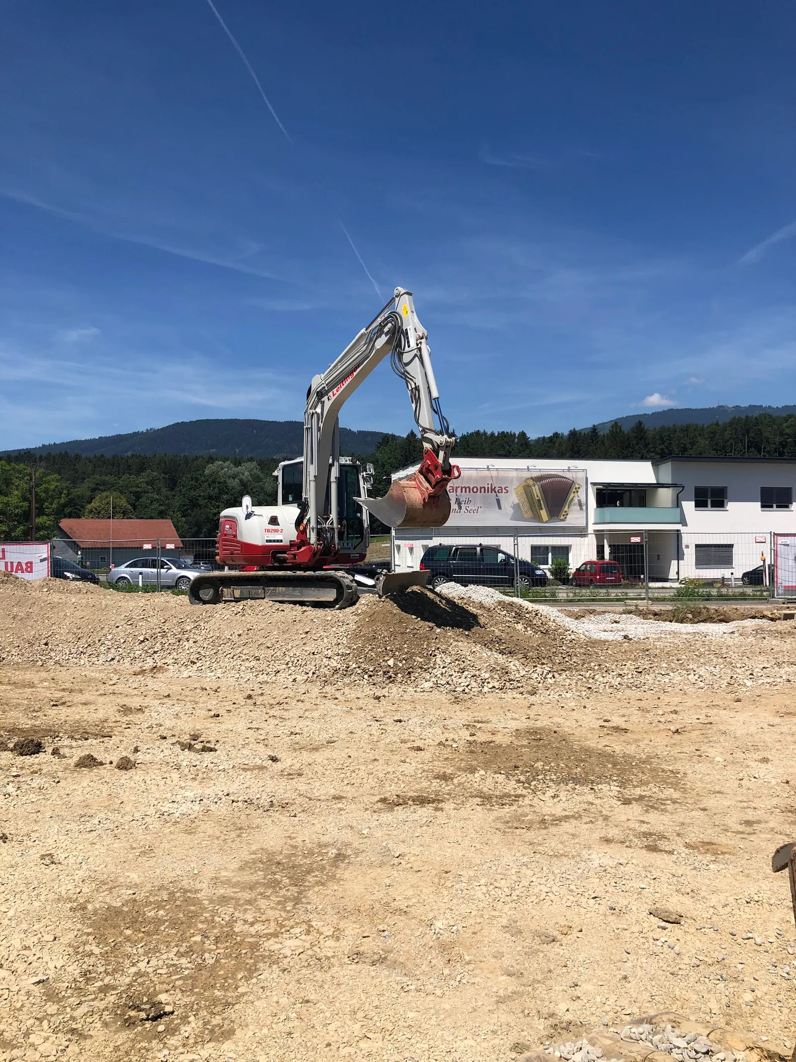 Bagger auf einer großen Schotterfläche vor einem Gewerbebau