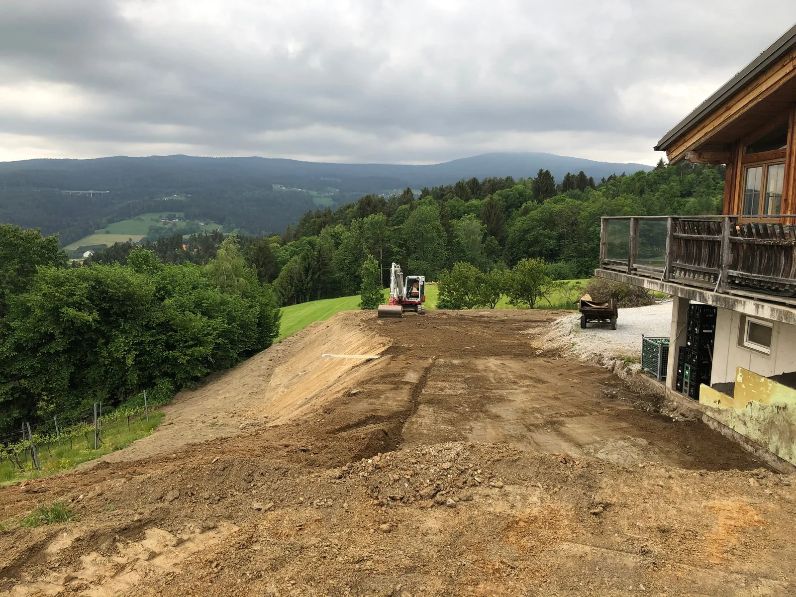 Planierte Hangfläche neben einem Holzhaus mit Blick über die Landschaft